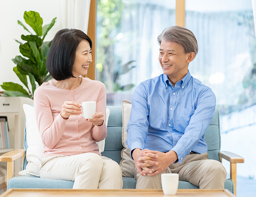 リビングで飲み物を持ち、微笑み合う熟年夫婦